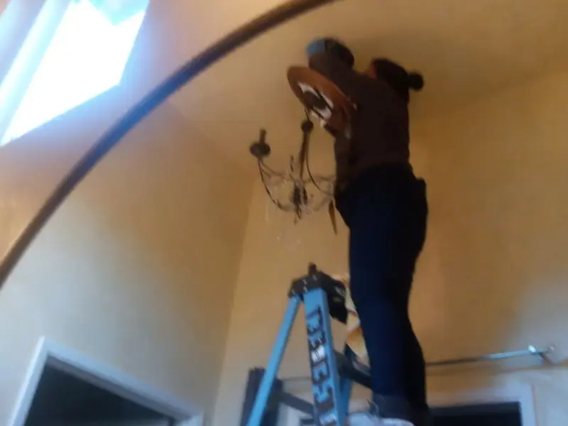 Electrician installing a chandelier in a Center residence